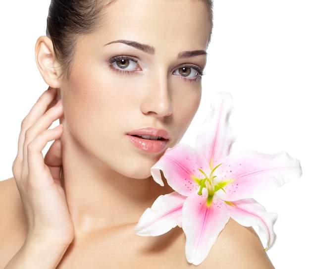 Beauty face of young woman with flower. Beauty treatment concept. Portrait over white wall