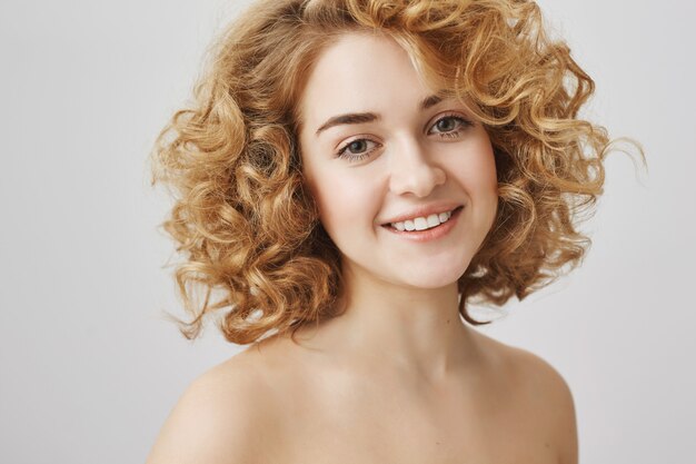 Beauty and fashion concept. Beautiful curly-haired girl with naked shoulders smiling