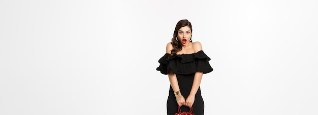 Beauty and fashion concept full length if silly young woman pouting and looking surprised holding pu