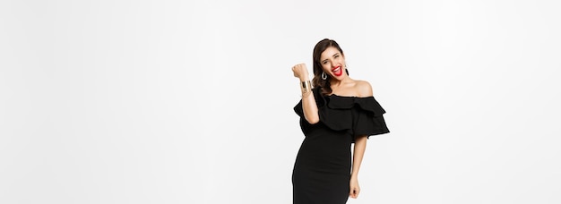 Free photo beauty and fashion concept full length shot of happy young woman in luxury black dress jewelry and h