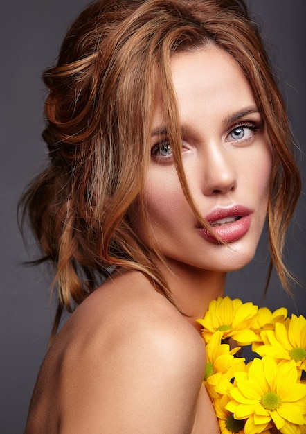 Портрет моды красоты молодой белокурой модели женщины с естественным составом и прекрасной кожей с ярко-желтым представлением цветка хризантемы