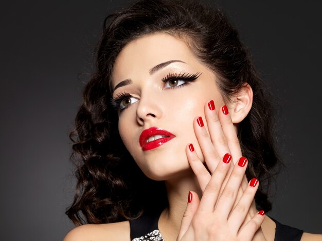 Beauty fashion woman with red nails, lips and golden eye makeup