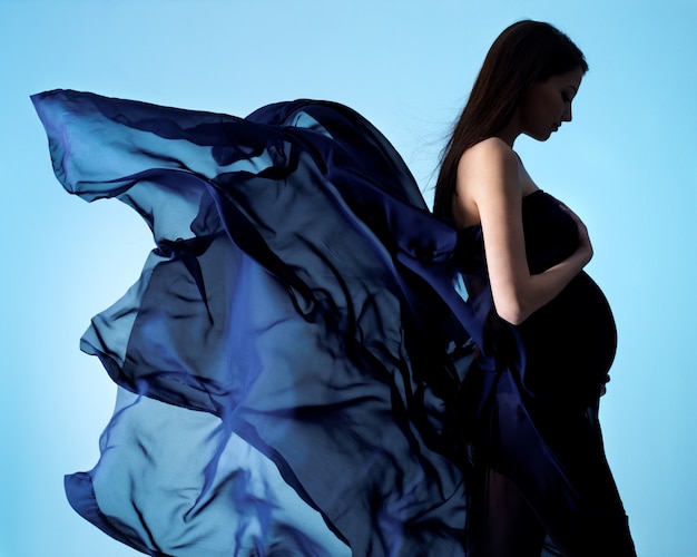 Beauty and glamour of young pregnant woman in blue chiffon on blue