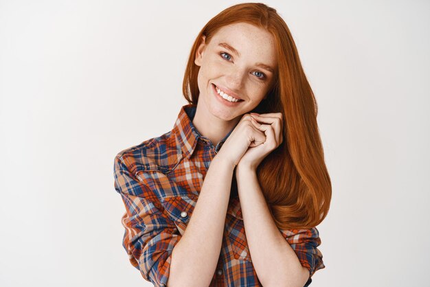 Beauty Image of beautiful redhead teenage girl admiring something looking dreamy at camera smiling with white teeth standing over white background