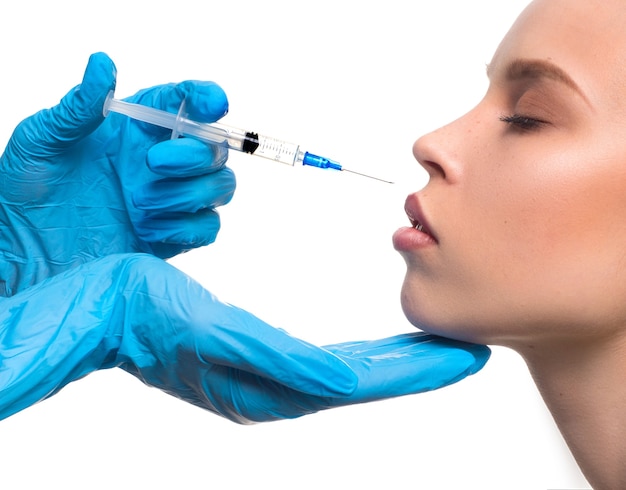 Beauty injections closeup view  gloved hands with a syringe inject botox into the lips operation to ...
