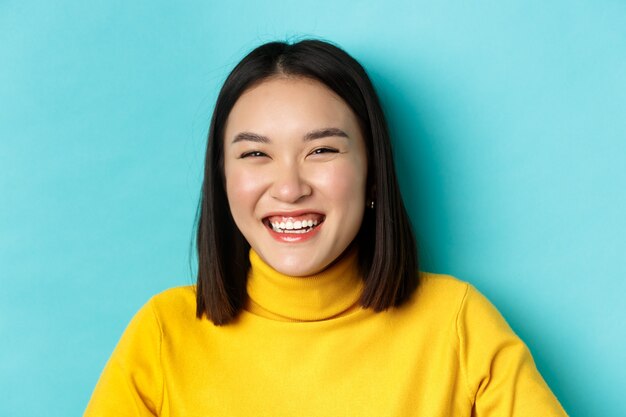 Beauty and makeup concept. Close up of carefree teenage girl smiling and laughing sincere, having fun, standing over blue background