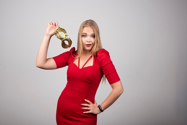 Beauty model woman holding a venetian golden masquerade carnival mask