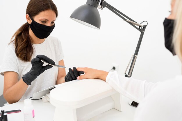 Beauty nail worker wearing face mask and gloves