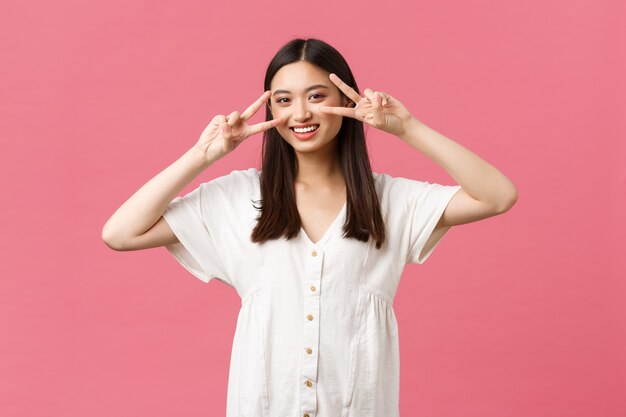 Beauty, people emotions and summer leisure and vacation concept. Pretty glamour and cute asian girl showing peace kawaii gestures near face and smiling, advertise skincare or cosmetics product.