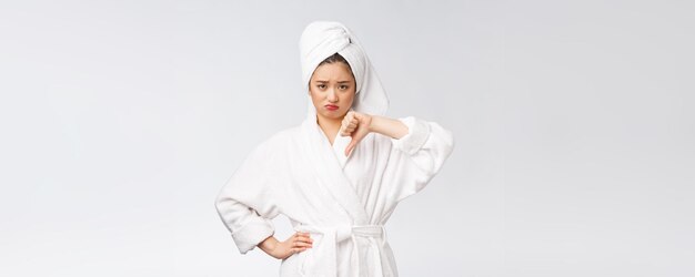 Beauty portrait asian woman looking on camera showing thumb down isolated over white background copy space