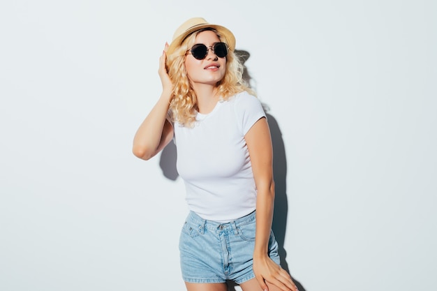 Free photo beauty portrait of a blonde woman eating lollipop and looking away isolated over white wall