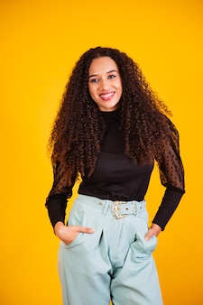 Beauty portrait of a brazilian woman with afro hairstyle and glamour makeup. latin woman. mixed race. curly hair. hair style. yellow background