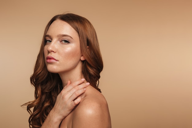 Beauty portrait of calm ginger woman with long hair posing sideways and looking