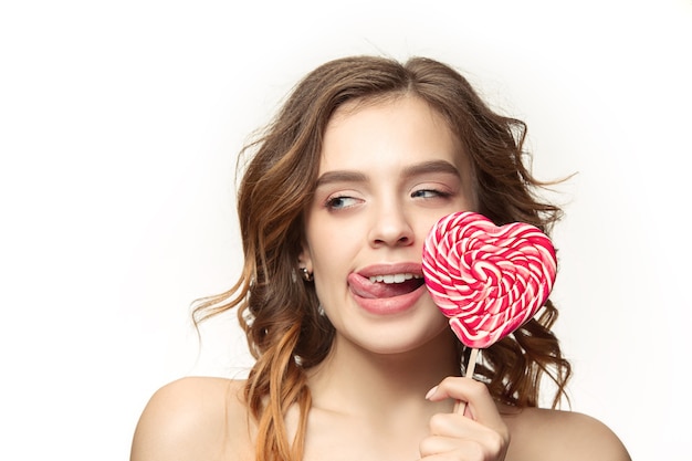 Красота портрет милой девушки в действии, чтобы съесть конфету на белом