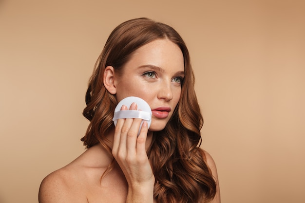 Beauty portrait of mystery ginger woman with long hair looking away while removing make up on her cheek