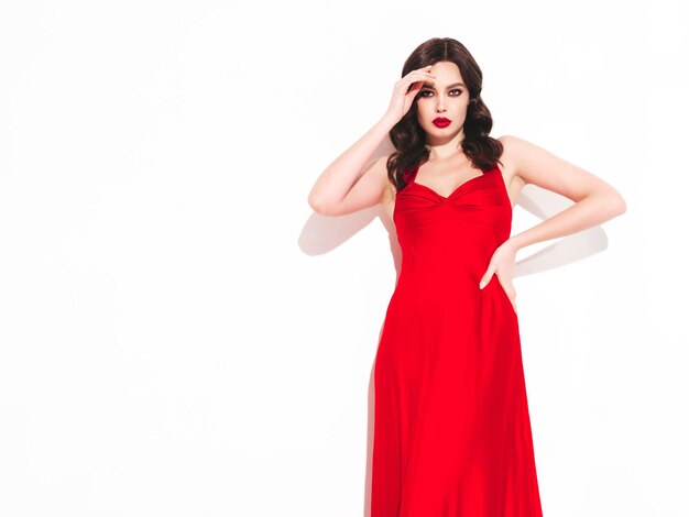 Beauty portrait of young brunette woman with evening makeup and perfect clean skin Sexy model with curly hair posing in studio With red bright natural lips Isolated on white In dress