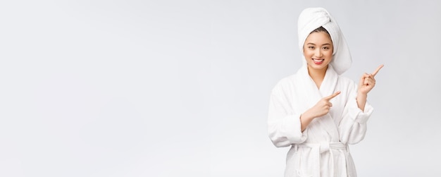 Beauty portrait of young woman showing and pointing finger to empty copy space asian beauty in bathrobe