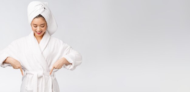 Beauty portrait of young woman showing and pointing finger to empty copy space asian beauty in bathrobe