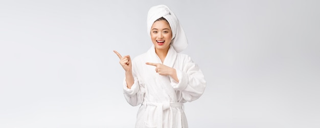 Портрет красоты молодой женщины, показывающей и указывающей пальцем на пустое пространство для копирования азиатской красоты в халате