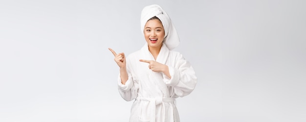 Beauty portrait of young woman showing and pointing finger to empty copy space asian beauty in bathrobe