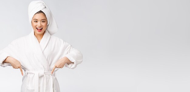 Beauty portrait of young woman showing and pointing finger to empty copy space asian beauty in bathrobe