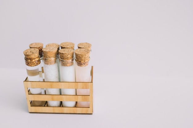 Beauty products test tubes in wooden container on white backdrop