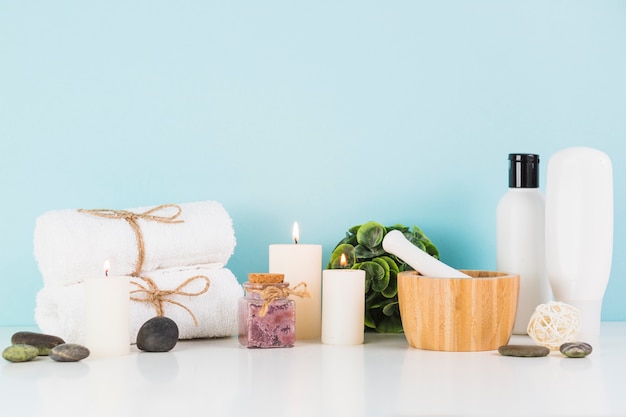 Beauty products with illuminated candles in front of blue wall