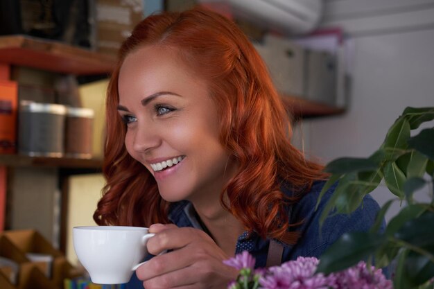 아름다운 빨간 머리 여성 바리스타가 커피숍에서 커피를 마십니다.