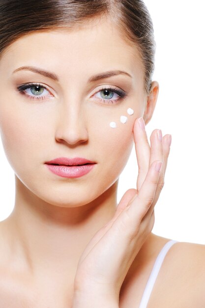 Beauty serene female face with a drops of  moisturizer cream on the skin under eyes