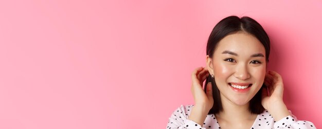 Beauty and skin care concept closeup of adorable smiling asian woman tuck hair behind ears blushing