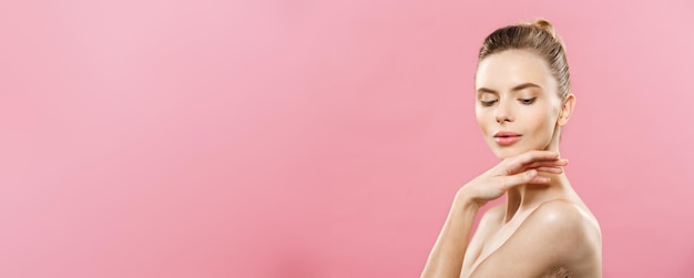 Foto gratuita concetto di pelle di bellezza bella giovane donna caucasica con pelle fresca e pulita distoglie lo sguardo con studi rosa