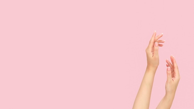 Beauty and skincare concept. beautiful young female hands after spa treatment on light pink background, copy space