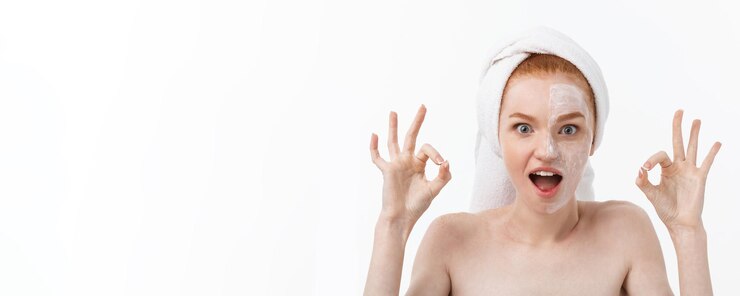 Free Photo beauty treatment woman applying moisturizing cream skin care product on face making ok sign studio s