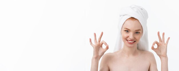 Beauty treatment woman applying moisturizing cream skin care product on face making ok sign studio s