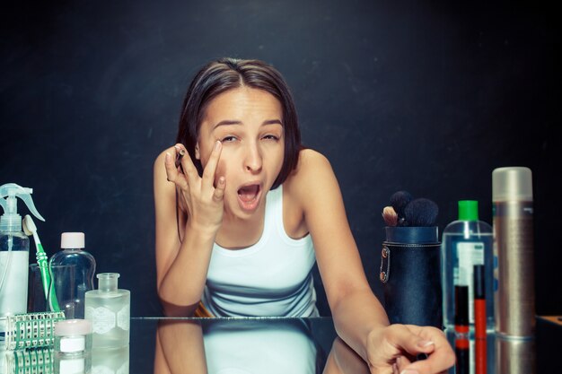 Beauty woman applying makeup. Beautiful girl looking in the mirror and applying cosmetic with a Eyeliner.