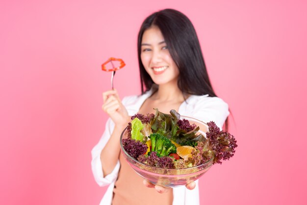Красота женщины Азиатская милая девушка чувствовать себя счастливой едят диетическое питание свежий салат для хорошего здоровья на розовом фоне