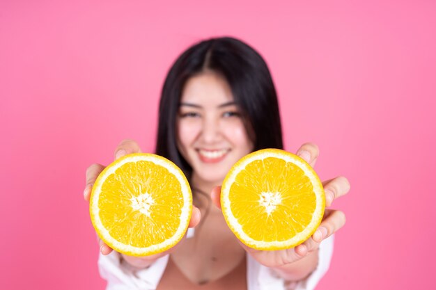 Красота женщина Азиатская милая девушка чувствовать себя счастливым Holdind оранжевый плод для хорошего здоровья на розовом фоне
