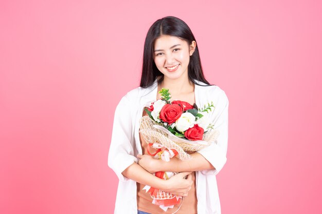 beauty woman Asian cute girl feel happy holding flower red rose and white rose on pink background