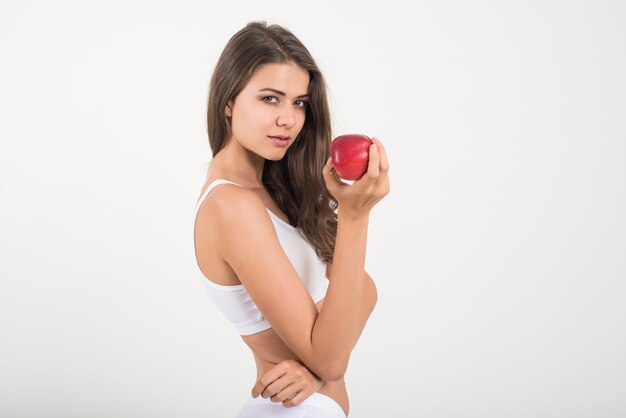 Красота женщины, держащей красное яблоко, в то время как изолированные на белом