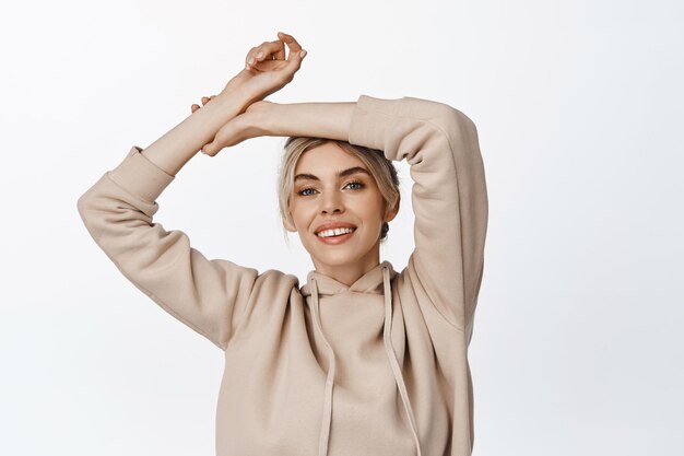 Beauty Young happy woman raising hands up and smiling carefree standing relaxed against white background