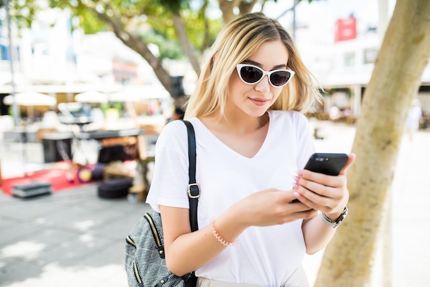 Красота молодой женщины с помощью смартфона на открытом воздухе на солнечной летней улице