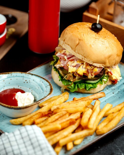Beef burger served with french fries ketchup and mayonnaise
