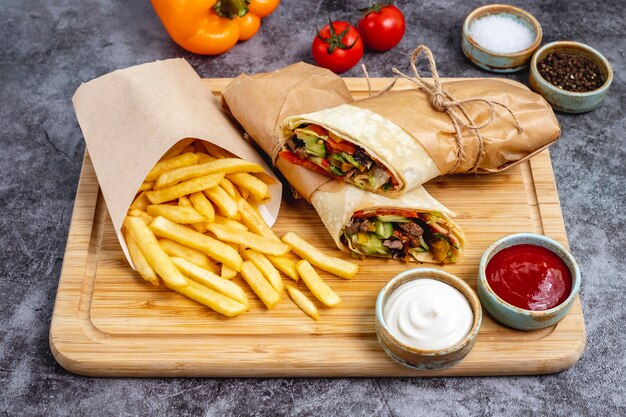 Beef burrito with tomato cucumber lettuce jalapeno served with fries and sauces horizontal