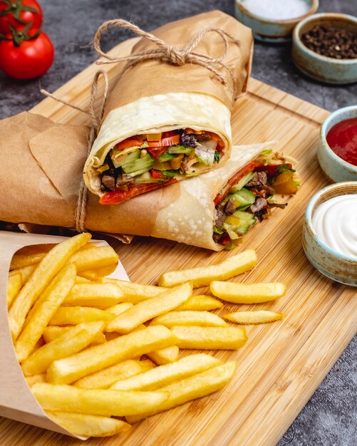 Beef burrito with tomato cucumber lettuce jalapeno served with fries and sauces vertical