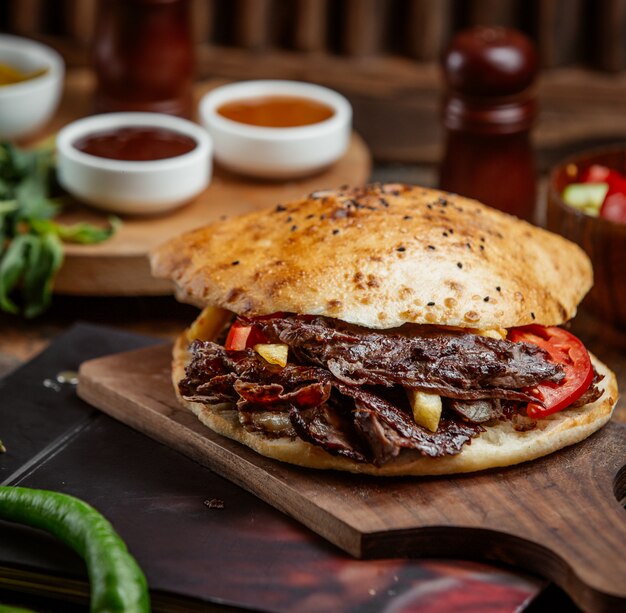 Beef doner with bread stuffed with potato, fries served on wood board