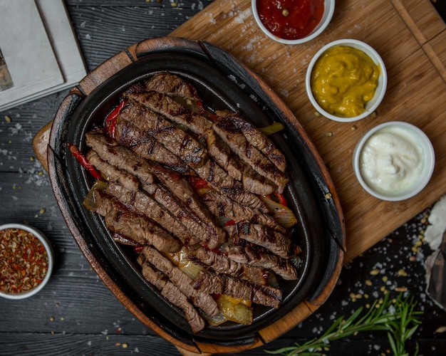 Beef fajitas with three kind of sauces on a wooden board