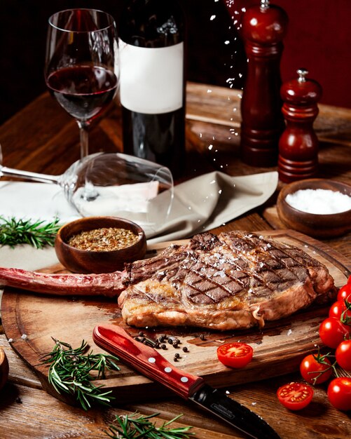 Beef steak garnished with kosher salt on wood serving board