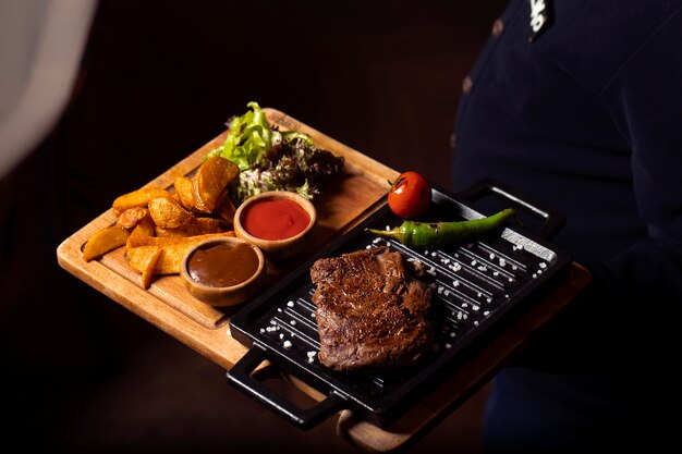 beef steak on mini grill pan served with fried potatoes, fresh salad