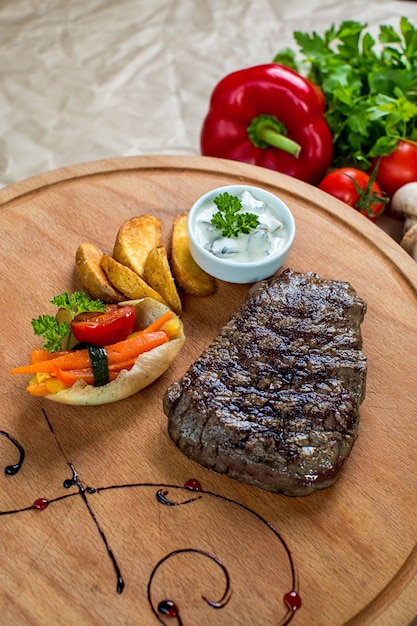 Beef steak served with fries and boiled vegetables in wood platter