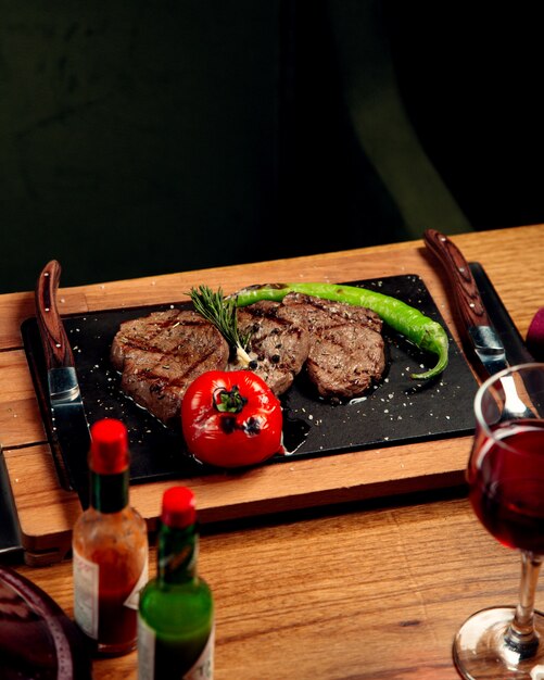 Beef steaks served with grilled tomato and pepper